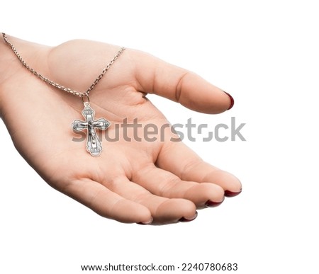 isolated on white background jewelry silver cross on a chain with a shadow lies on the hand of a girl model