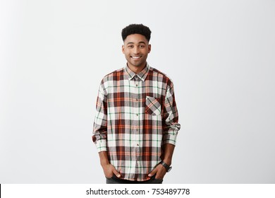 Isolated on white background. People and emotions. Young good-looking dark-skinned man smiling, wearing checkered shirt. looking in camera with happy and relaxed face expression - Powered by Shutterstock