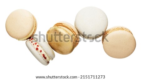 Isolated on white background white, yellow, gold macaron cookies flying, falling in motion or levitating. Colorful, sweet small French macaroon cakes. Five full cookies isolate. High quality photo