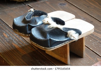 Isolated Pair Of Tall Wooden Japanese Shoes Made Black Leather With White Fur Trim.