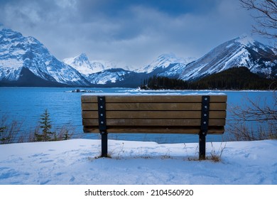 An isolated park bench overlooking the Upper Kananaskis Lake and Canadian Rocky Mountains in Alberta Canada
