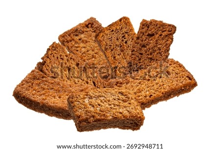 Isolated photograph of a pile of crispy, rectangular, dark brown bread rusks or toasted rye croutons arranged loosely and isolated on a white background.