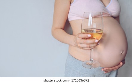 Isolated portrait of unrecognizable pregnant woman holding glass of wine and showing her big belly. Pregnancy, motherhood, unborn and expectation. Bad habits concept. Free space for text mockup