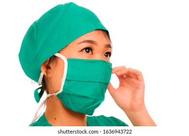 Isolated Portrait Of Young Beautiful And Serious Asian Korean Medicine Doctor Woman Or Hospital Nurse In Medical Hat Surgeon Face Mask And Green Scrub In China Flu Virus Outbreak Concept