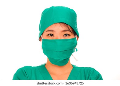 Isolated Portrait Of Young Beautiful And Serious Asian Korean Medicine Doctor Woman Or Hospital Nurse In Medical Hat Surgeon Face Mask And Green Scrub In China Flu Virus Outbreak Concept