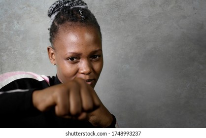 Isolated Portrait Of Young Cool And Confident Black Afro American Woman In Fighting Stance Looking Defiant Rising Her Fist Throwing Punch In Badass Attitude Isolated On Grunge Background