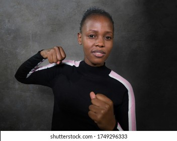 Isolated Portrait Of Young Cool And Confident Black Afro American Woman In Fighting Stance Looking Defiant Rising Her Fist Throwing Punch In Badass Attitude Isolated On Grunge Background