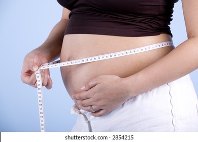 Isolated Pregnant woman measuring her belly shot over blue background - Powered by Shutterstock