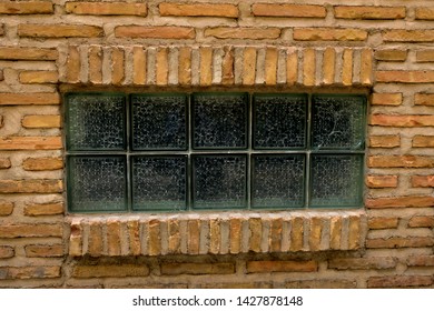 Isolated rectangular window made of frosted glass squares on a brick wall.