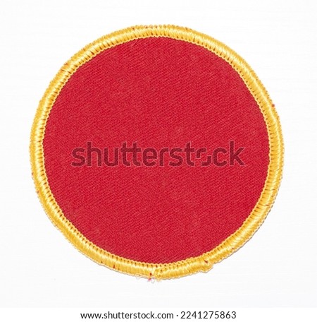 Isolated red circle patch with gold trim.