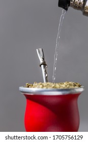 Isolated Red Gourd With Latin American Ilex Paraguariensis Tea Infusion Yerba Mate, National Drink Of Uruguay And Argentina. Hot Water Poured Into With Mate Alpacca Bombilla Or Metal Straw To Filter