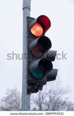 Isolated red traffic light glowing clearly during daytime, captured in a sharp close-up view.