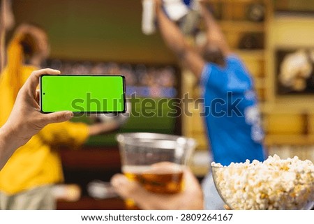 Isolated screen smartphone used by soccer fan in living room to watch video highlights of sports game, while mockup mobile phone used by football fan in apartment home to replay goals scored.