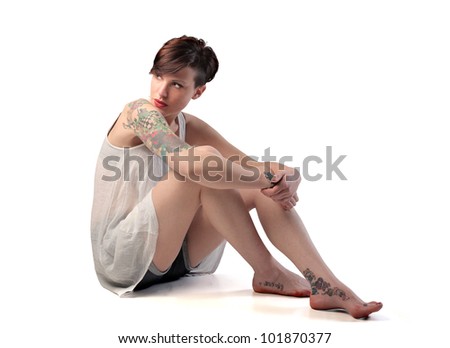 Isolated seated beautiful woman with tattoos on her arm and ankles