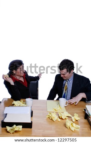 An isolated shot of a businessman and businesswoman sitting at desk throwing yellow paper at each other.