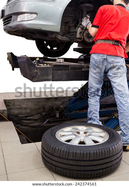 Isolated shot of a mechanic servicing the brake\
system, with tire on the\
floor.