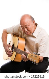 An isolated shot of a senior asian man playing guitar
