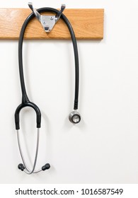 An isolated Stethoscope hangs from a coat rack hook in a hospital room.