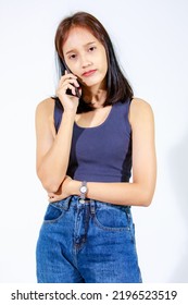 Isolated Studio Cutout Shot Of Asian Young Female Teenager Model In Crop Top Shirt And Jeans Holding Smartphone On White Background