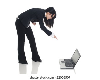 Isolated studio shot of a businesswoman leaning over and pointing angrily at a laptop.