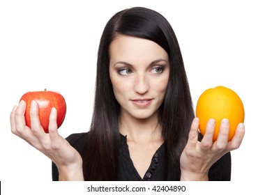 Isolated studio shot of a dark haired caucasian woman comparing apples to oranges.