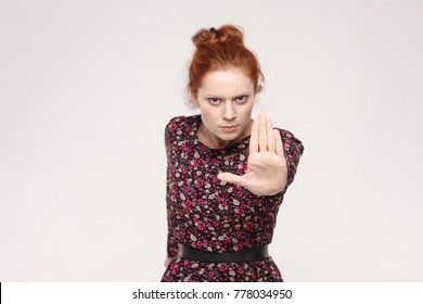Isolated studio shot on gray background. Redhead woman with bad attitude making stop gesture with her palm outward, saying no, expressing denial or restriction. Focus on hand. - Shutterstock ID 778034950
