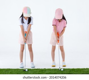 Isolated studio shot of two pretty cute little Asian golfer sister in sport athlete uniform standing together holding putter ready to putting golf ball on green grass in front of white background. - Powered by Shutterstock