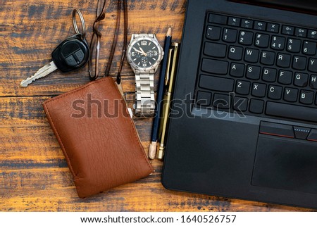 Isolated top view of office table with laptop, pen,pencil,watch,glass, car key & man wallet