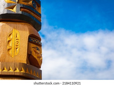Isolated totem wood pole in blue sky background. Indian totem poles in park in Nanaimo, Canada. Travel photo, copy space for text, nobody