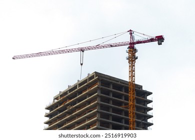 Isolated tower-type construction crane during the construction of a monolithic skyscraper, a high-rise multi-storey residential building on a white background. Blank for artworks - Powered by Shutterstock