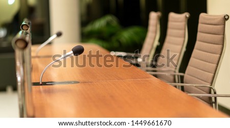 Isolated view of a microphone in a meeting room on a table with blurred chairs - close-up with selective focus, very little depth of field and much copyspace