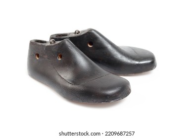 Isolated vintage shoe form child size. Pair of dark wooden cobbler shoe molds for children. Used by shoe makers or cordwainer for manufacturing or repairing shoes. Selective focus. White background.