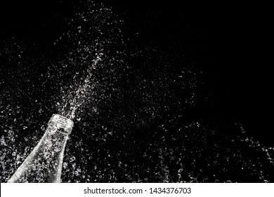 Isolated Water Splash From Bottle On Black Background , Sparkling Mineral Water With Waterdrops, Fizzing Refreshment Close Up