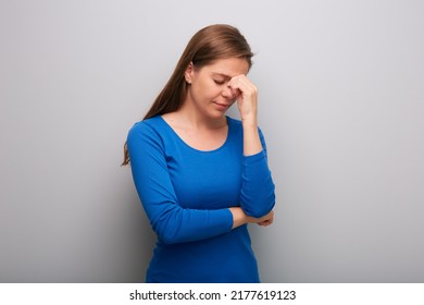 Isolated Woman Headache With Hands On Head. Female Portrait With Closed Eyes In Blue Shirt. Head Tilt Down.