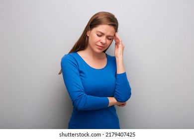 Isolated Woman Headache With Hands On Head. Female Portrait With Closed Eyes In Blue Shirt. Head Tilt Down.