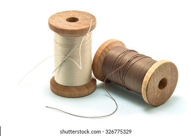 Isolated Wooden Spool Of Thread And Needle