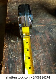 An Isolated Yellow Tape Measure On A Wooden Surface Work Bench