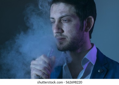 Isolated young man on a black background holding an electronic cigarette, vaping device, mod.