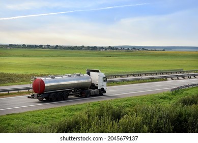 Isothermal Tank truck driving on highway. Oil and Gas Transportation and Logistics. Metal chrome cistern tanker with petrochemicals. Out of focus, possible granularity, sharpening noise.
