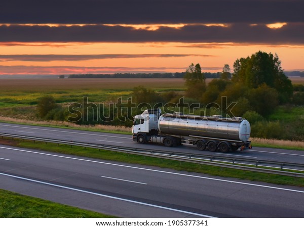 Isothermal Tank truck driving on highway. Oil and\
Gas Transportation and Logistics. Metal chrome cistern tanker with\
petrochemicals products. Liquid Chemical Freight. Out of\
focus\

