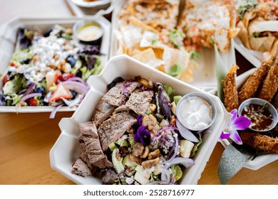 isplay of assorted gourmet takeout dishes artfully arranged on a wooden table. Each biodegradable container holds a different dish, from grilled shrimp and fries to mixed greens topped. - Powered by Shutterstock