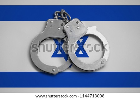 Israel flag  and police handcuffs. The concept of observance of the law in the country and protection from crime