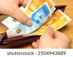 Israel money. Hand taking money out of wallet. Israeli shekels, financial concept