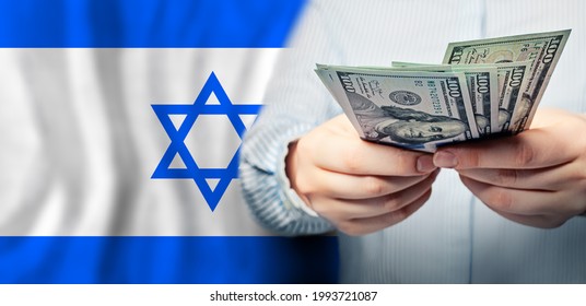 Israel politics, business and social problems concept. US dollars banknotes in hand on Jewish flag background