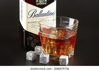 Israel. Rishon LeZion. 08.14.2021. A bottle of whiskey "Ballantines", a glass of whiskey with ice and whiskey stones on a black background close-up.
