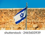 Israeli flag fluttering against Western wall in Jerusalem in Israel