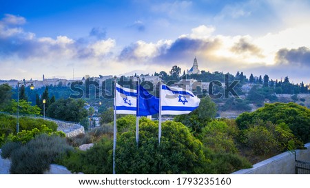 Israeli flags with beautiful sunrise view of Mount Zion: Dormition Abbey, Jerusalem university college and greek ceminary; with walls of Jerusalem's Old City, leading up to the Tower of David