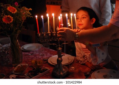 Israeli Jewish family lighting all menorah candles on the 8th day of the Jewish holiday of Hanukkah.Real people. Copy space
