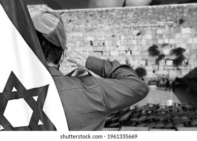 Israeli soldier with Flag of Israel salutes on the blurred background of Western Wall in the Old City of Jerusalem in Israel