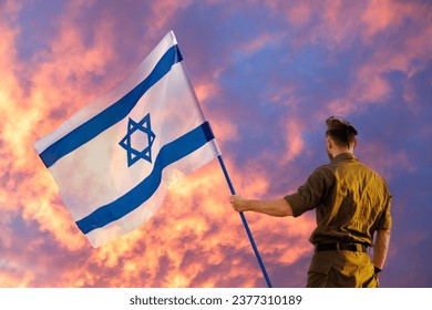 Soldado israelí con bandera israelí contra una puesta de sol feroz. Día del Recuerdo - Yom HaZikaron, fiesta patriótica, Día de la Independencia de Israel - concepto Yom Ha'atzmaut.